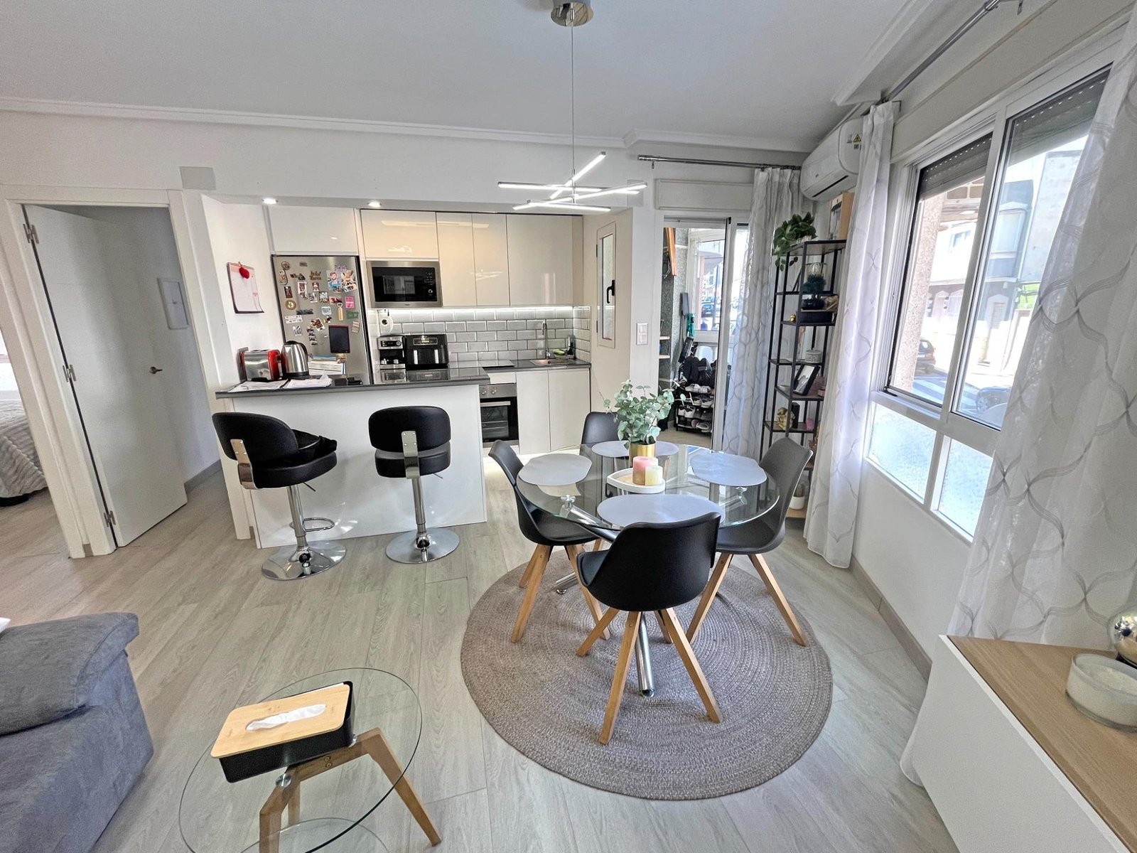 Comedor moderno con mesa circular y sillas negras en un apartamento luminoso