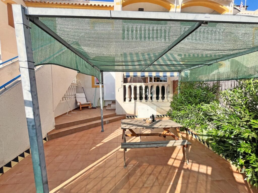 Espacio exterior con toldo y mesa de madera
