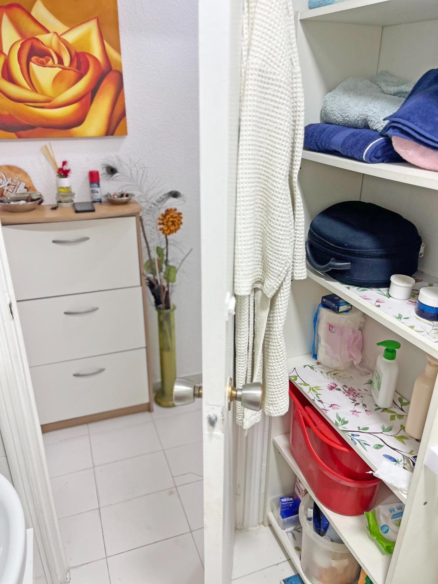 Puerta de baño abierta con estanterías