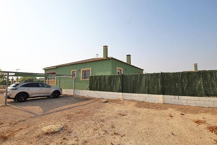 Casa verde con cercas y coche