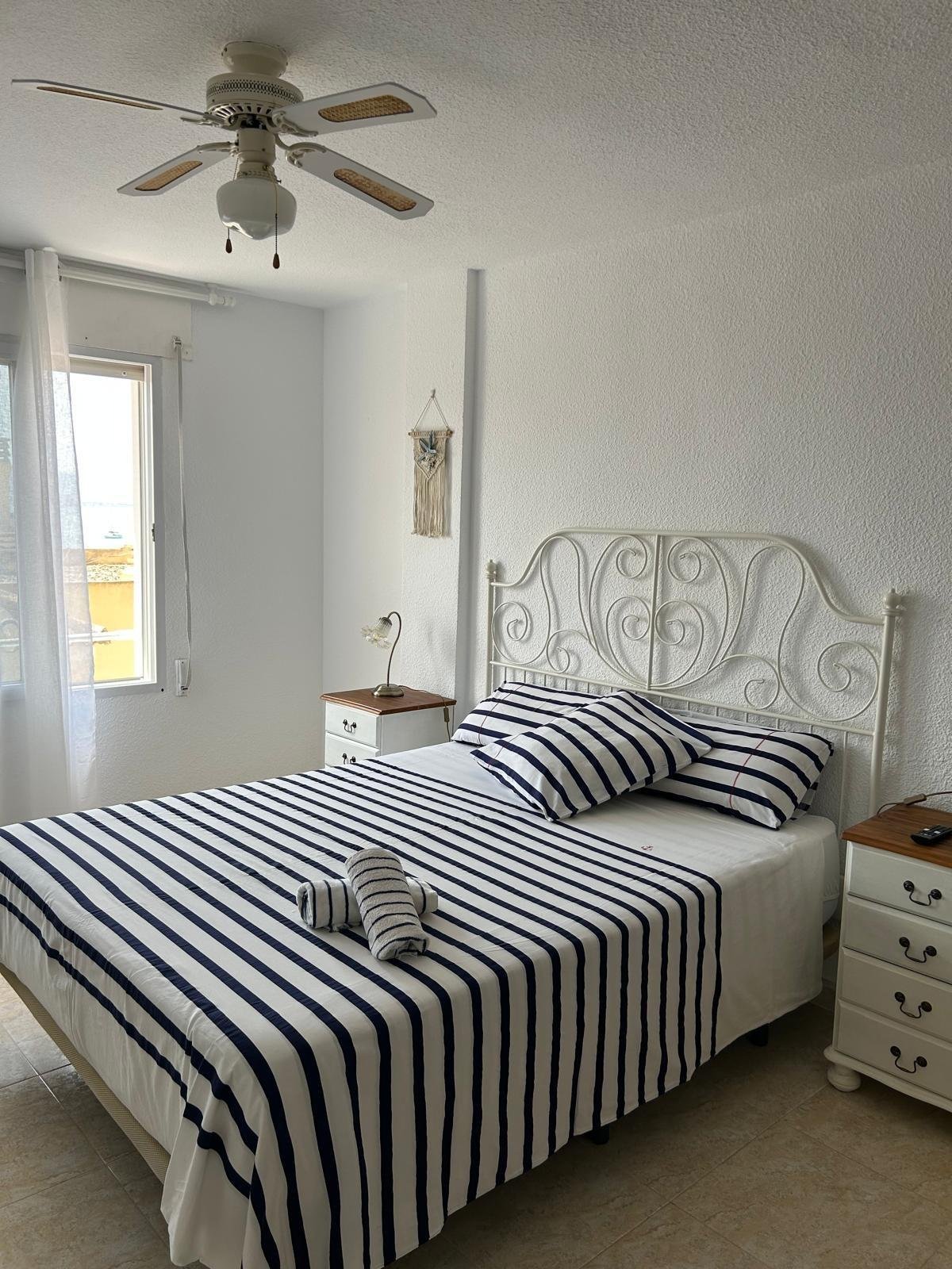 Dormitorio con cama blanca y rayas
